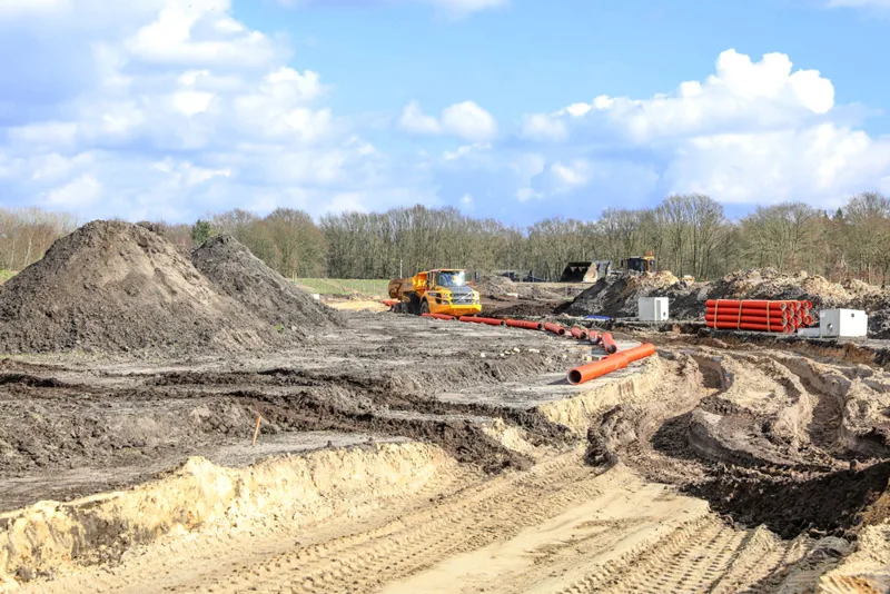 Zandhopen, graafsporen en materieel op een bouwterrein.